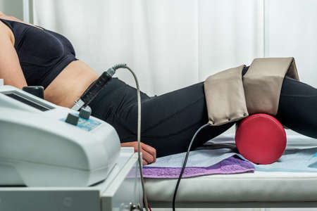 Magnet therapy system. Patient on a treatment bed with Magnetic Field Therapy on her leg. Medicine...