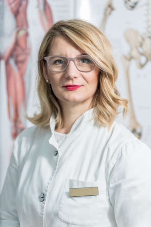 Blonde female physician doctor standing in Her office. Portrait of friendly smiling woman-physician. Medicine conceptの写真素材