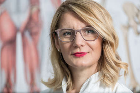 Blonde female physician doctor standing in Her office. Portrait of friendly smiling woman-physician. Medicine conceptの写真素材