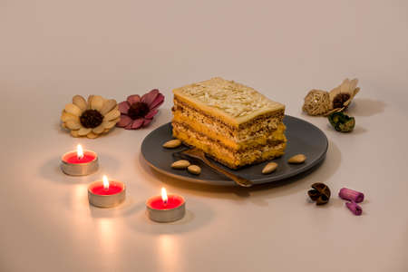 Slice of Queen Maria Cake with Walnuts and Almonds in a pink plate, with romantic candles set, closeup viewの写真素材