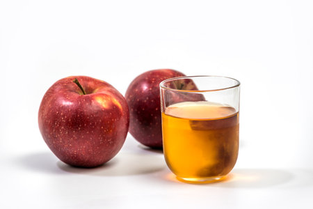 Close up of a glass of apple juice, with a whole and half apple. Natural apple juice on white backgroundの写真素材