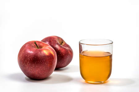 Close up of a glass of apple juice, with a whole and half apple. Natural apple juice on white backgroundの写真素材