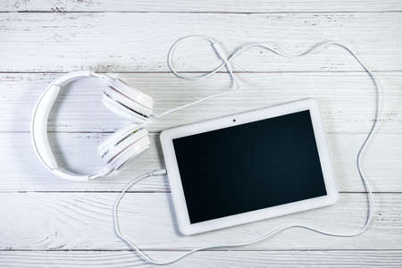 Tablet pc and Headphones on white wooden surface. Music tablet mockup. Clipping path for screen copy spaceの写真素材