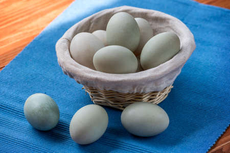 Fresh duck eggs collect from farm products natural in a wicker basket healthy eating concept. blue cloth backgroundの写真素材
