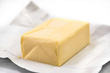 Traditional butter block unwrapped for use as a baking ingredient isolated on white background. Close up of a Butter Blockの写真素材