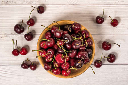 Bowl full of ripe red dark cherries on wooden table surface as Source of vitamins, organic food. Top Viewの写真素材
