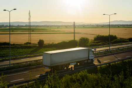 White Truck with semi-trailer driving along highway on the sunset sky and rural background. Services and Transport logisticsの写真素材