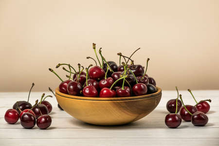 Bowl full of ripe red dark cherries on wooden table surface as Source of vitamins, organic foodの写真素材