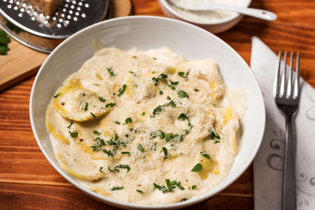 Ravioli with mushrooms, Parmigiano, parsley and fresh basil. Wooden table setup. Close upの写真素材
