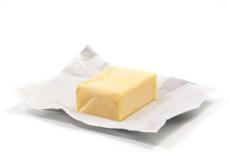 Traditional butter block unwrapped for use as a baking ingredient isolated on white background. Close up of a Butter Blockの写真素材