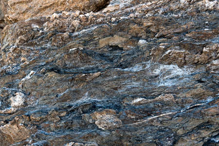 Dark Volcanic rock surface texture with colored spots. Rock formations of Volcanic rock or vulcanite. Volcanic soil shapes. Organic and natural textures. Geologic detailsの写真素材