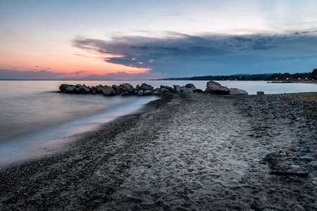Tropical beach on beautiful sunset. Nature seascape background. Sun setting in waves of Aegean sea in Greeceの写真素材