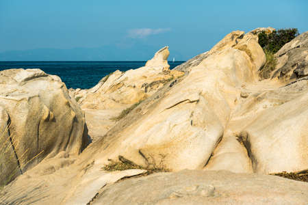 Seascape of rocky beach with beautiful rocks formations. Sea waves crash and splash on rocks. View of the sea, ocean. Natural soft blue background.の写真素材
