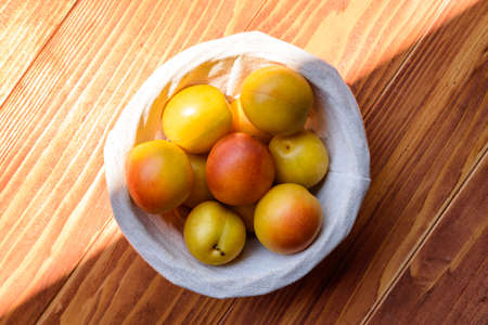 Mirabelle Plums in a basket on a wooden table. Top Viewの写真素材