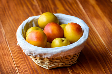 Mirabelle Plums in a basket on a wooden tableの写真素材