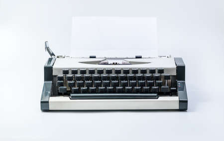 Old vintage typewriter and a blank sheet of white paper inserted. Isolated on white background.