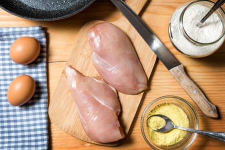 Chicken fillet on a cutting board ready for grilling. Raw chicken breast with grill pan, flour and spices. Chicken steaks for cooking. Top viewの写真素材