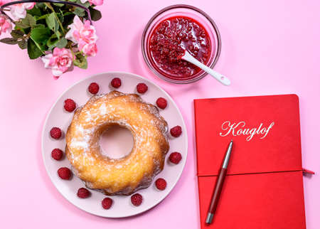 Homemade Kouglof cake with icing sugar dressing, Raspberries and Raspberry Filling, along Red Book of Recipes. Gugelhupf, Kugelhupf or Christmas Cake. Top Viewの写真素材