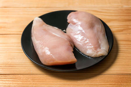 Chicken fillet in a black plate ready for grilling. Chicken steaks for cookingの写真素材
