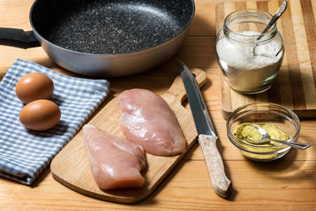 Chicken fillet on a cutting board ready for grilling. Raw chicken breast with grill pan, flour and spices. Chicken steaks for cookingの写真素材