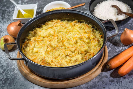 Italian vegan Risotto in a large pan with ingredients - rice, onion, carrots, spices, olive oilの写真素材