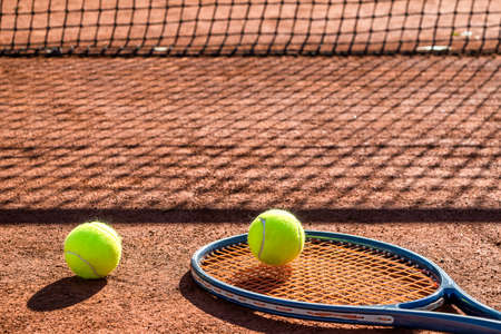 Tennis racket and new tennis ball on a Red clay court.の写真素材