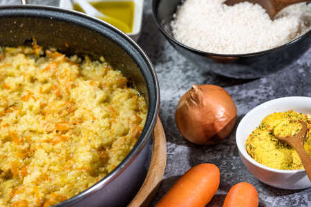 Italian vegan Risotto in a large pan with ingredients - rice, onion, carrots, spices, olive oilの写真素材
