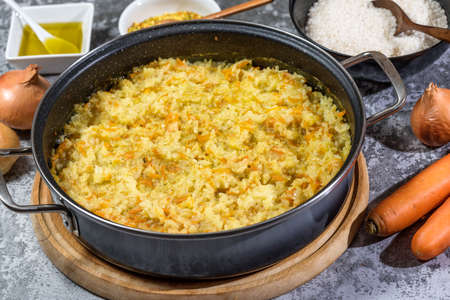 Italian vegan Risotto in a large pan with ingredients - rice, onion, carrots, spices, olive oilの写真素材