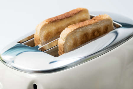 Slices of bread are prepared for breakfast. The toaster has two crispy toasts.の写真素材