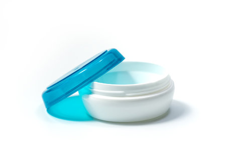 Empty White Plastic opaque cream jar with blue translucent lid. Isolated on white background. Cosmetic product for skin careの写真素材