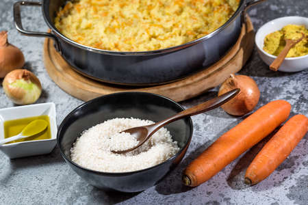 Italian vegan Risotto in a large pan with ingredients - rice, onion, carrots, spices, olive oilの写真素材