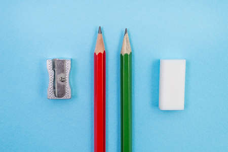 Two pencils, sharpener and eraser on blue background. Top view. School conceptの写真素材