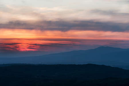 Sunset with layers of hills and mountains, soft focus. Mountain layers in sunset. Blue mountains and last sun lights landscape.の写真素材