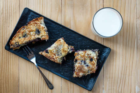 Homemade delicious sliced Apple Blueberry Pie on a black serving plate on a wooden table with a glass of milk. Top Viewの写真素材