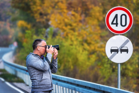 Photographer walks down a road in the autumn with his camera, taking photos. Selective Focusの写真素材