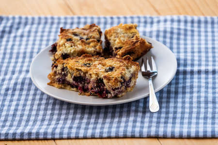 Homemade delicious sliced Apple Blueberry Pie on a white plate on a wooden table with fork and a blue cloth.の写真素材