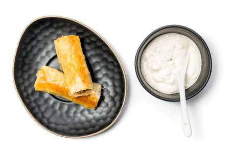 Meat rolls pastry - fried minced pork meat in spring rolls in a black oval plate, with a bowl of tartar sauce, isolated on white background with clipping path included. Top Viewの写真素材