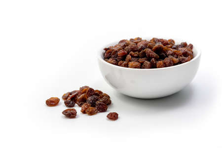 Brown raisins in white bowl isolated on white backgroundの写真素材