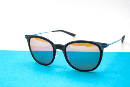 Conceptual elegant Sunglasses on blue and white background. Sun glasses summer accessories as design...