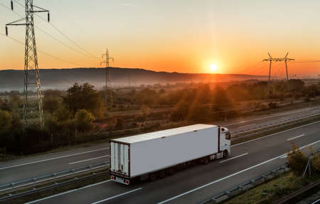 White Transportation truck along the highway in dreamy sunset. Highway transportation with setting...