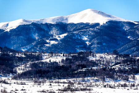 Winter landscape with high snowy mountain with peaked top in sky. Atmospheric view to big snow covered mountains in sunshine.の写真素材