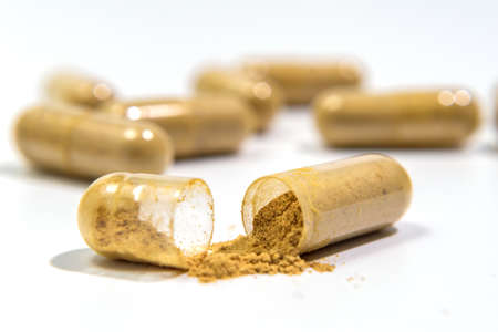 Capsules with bio additives. Tablets and capsules as a treatment of a disease. Capsule with natural supplements on white table background. Macro with Selective focusの写真素材