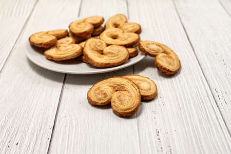 Palmier puff pastry biscuits in white plate on a white painted wooden tableの写真素材