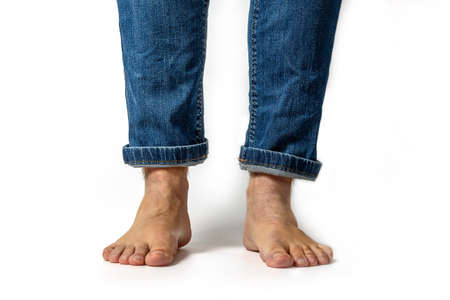 Closeup of unrecognizable young caucasian man feet and wearing denim jeans pants isolated on white backgroundの写真素材