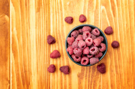 Ripe sweet raspberries in bowl on wooden table. Top Viewの写真素材
