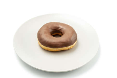 Tasty Donut dessert with chocolate glossy glaze in a plate, isolated on white background. One round chocolate doughnut cake for your design and printの写真素材