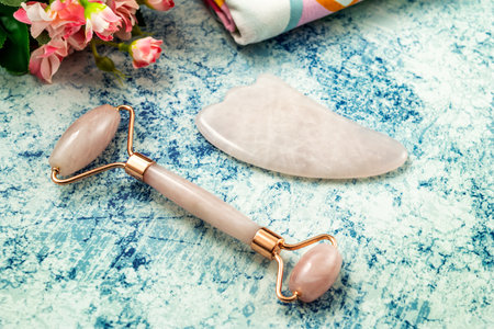 Jade Roller and Gua Sha for beauty facial massage therapy with towel. Flat lay on marble backgroundの写真素材
