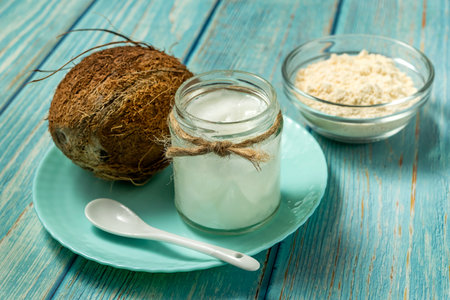 Coconut oil in jar, coconut protein in bowl and fresh coconuts on old vlue wooden tableの写真素材
