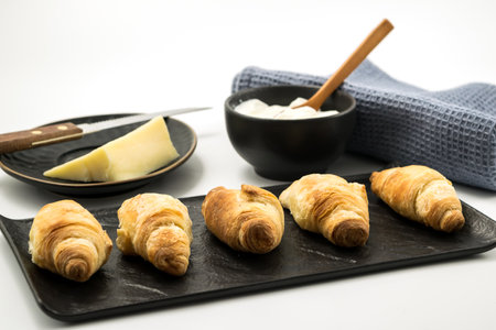 Traditional rolled dough called Kiflice served wuth chease and yogurt on black plate and white backgroundの写真素材