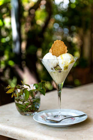 Selective focus of Italian gelato, milky ice cream dessert with pistachio on the outdoors garden tableの写真素材